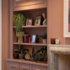 Photo of a lounge in a modern home, featuring pink painted bespoke cabinetry with decorative mouldings installed