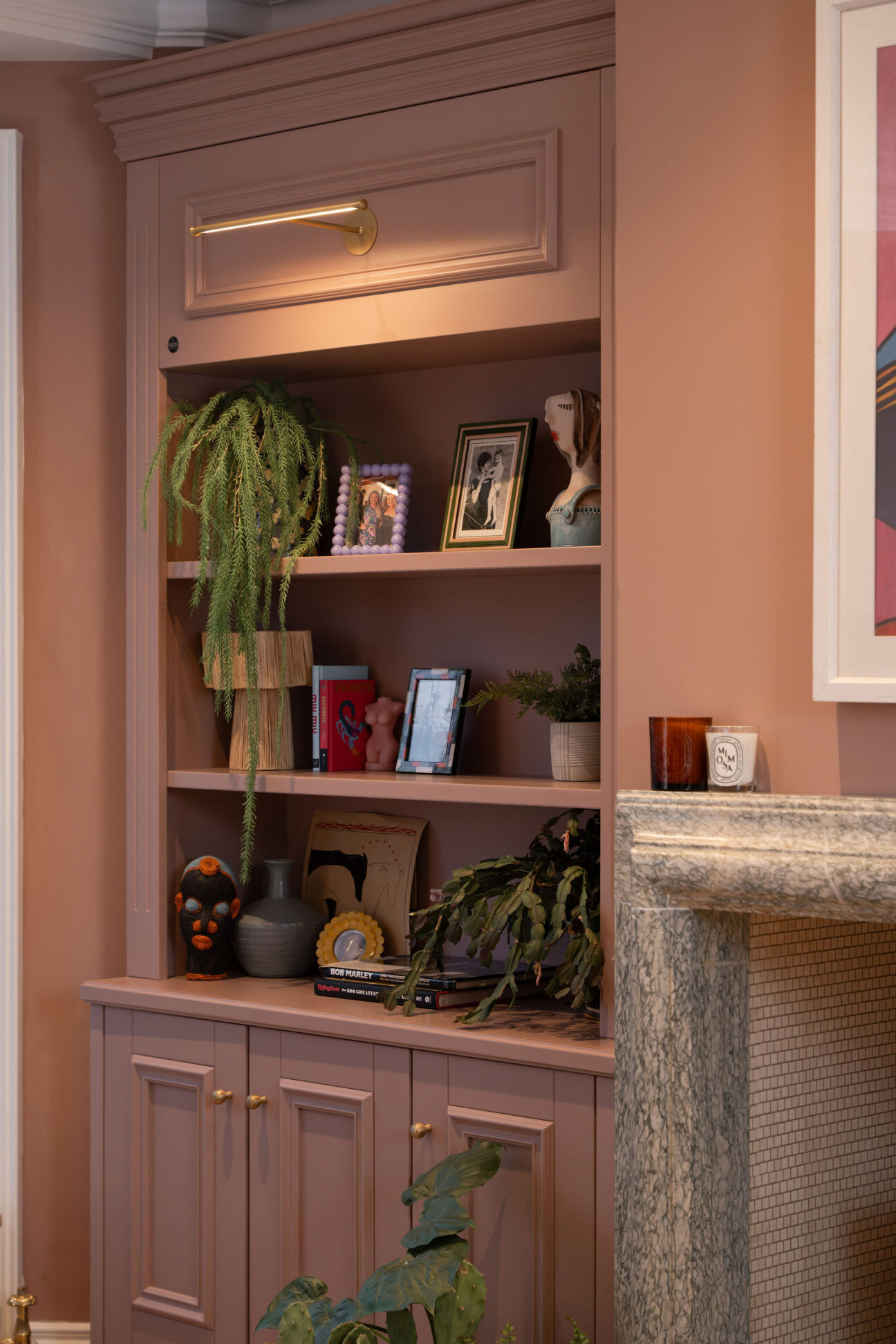 Photo of a lounge in a modern home, featuring pink painted bespoke cabinetry with decorative mouldings installed